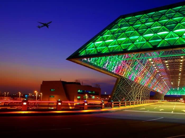 Colorful illuminated architectural design in an airport, showcasing vibrant lime and mint hues in a modern setting.