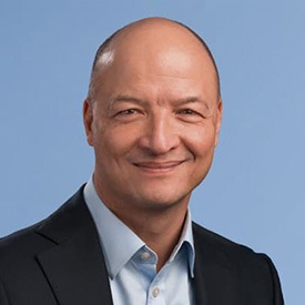 A professional portrait of Alex Klein, a man with short dark hair, wearing a suit and tie, smiling confidently.